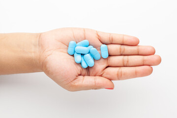 Macro Close up of medicinal or herbal cyan tablet on female hand palm. Top view, white background.