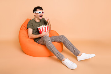 Photo of guy sit beanbag hold box popcorn look empty space wear 3d glasses green t-shirt isolated...