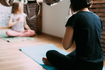 Two women sit on a mat in a yoga class and meditate after a workout. Rest, relaxation, meditation