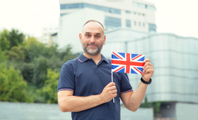 Mature man with the flag of Great Britain on the background of the city. Travel and learn English