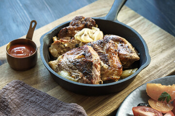Roasted sliced pork steaks in frying pan on table, low shallow focus