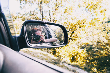 Selfie of a girl in the rear view of the car while the car is running.