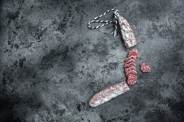 spanish fuet sausages cut in slices on a black background. top view
