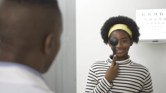 African teen girl reading eye chart during distance vision exam, health concept.