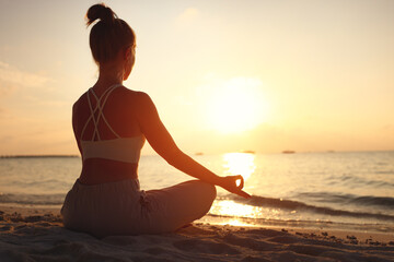 Calm woman meditating on beach at sunset