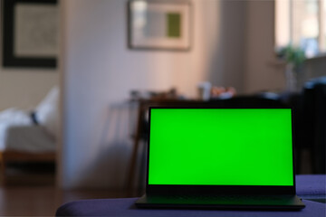 close up one green screen laptop computer at home. blurred home interior background