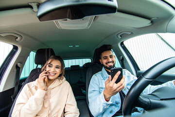 Young indian couple on the red car, man using moblie phones while drive car.