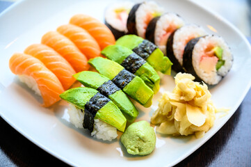 Assorted sushi set of sushi rolls and nigiri on a white plate with wasabi and ginger on the side