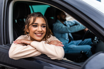 Obraz na płótnie Canvas Enjoying travel. Beautiful young indian couple sitting on the front passenger seats and smiling while handsome man driving a car