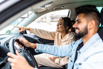 Enjoy life fun indian couple driving car at high speed and point fingers forward.