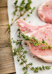 Raw pork meat with thyme and spices on the rustic background. Selective focus. Shallow depth of field. 