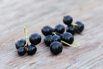 few sprigs with ripe blackcurrant berries on wooden surface, selective focus. Natural vitamins.