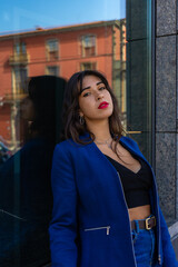 Fototapeta premium Young woman posing for a portrait in the background looks a glass. She wears an American jacket and jeans. The photo was taken in La Laguna, Tenerife.