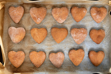 Freshly baked homemade shortbread cookies in shape of heart on baking sheet.