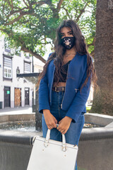 Fototapeta premium Young woman posing in a fountain holding a purse with mask. The photo was taken in La Laguna, Tenerife.