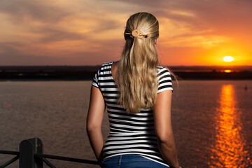 Mujer joven observando la puesta de sol en el mar,