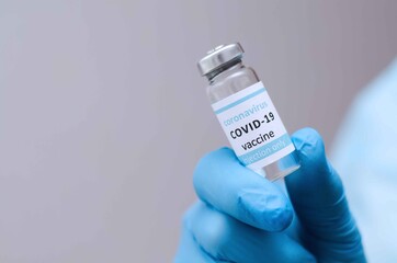 Doctor or laborant in protective gloves holding ampule tube with nCoV Coronavirus vaccine for COVID virus.