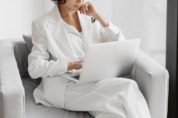 Cropped portrait of businesswoman working with laptop while siting in chair in office.