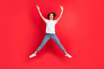 Full length body size view of attractive funky cheerful girl jumping having fun good mood isolated over bright red color background