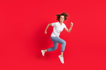 Fototapeta na wymiar Full length body size view of attractive cheerful girl jumping running action isolated over bright red color background