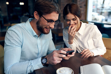 man and woman are sitting in a cafe at the table working