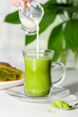 Japanese green tea Matcha in a glass cup  with flowing coconut milk.