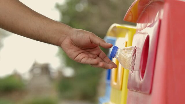 A young man drinks from plastic bottles and throws them into the trash. Video about environmental day Separate plastic waste in the correct category. Public trash