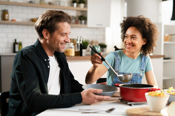 Boyfriend and girlfriend eating lunch with friends at home. Young couple enjoying the company of their friends