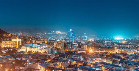 Fototapeta na wymiar Tbilisi, Georgia. Elevated Rooftop View In Night Illuminations. Georgian Capital Skyline Cityscape. Panorama, Panoramic Evening View