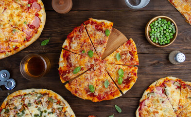 Pizzas with different fillings on a wooden table, top view