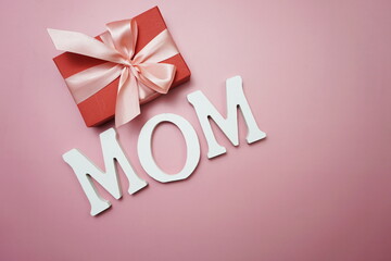 Fototapeta na wymiar MOM word and gift box present on pink background