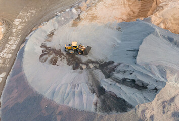 Aerial view of an open pit. Front loader transports gravel in a quarry. Out of focus