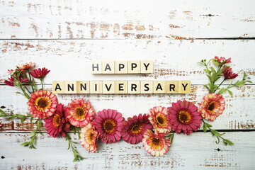 Happy Anniversary alphabet letter with flower decoration on wooden background