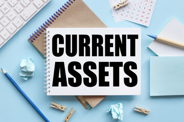 Current Assets. text on white notepad paper on blue background. near the blue sticks and a white keyboard