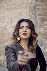 Naklejka premium Close-up front portrait of a cheerful young woman with makeup and hairstyle, stretch out one's hand on front camera.
