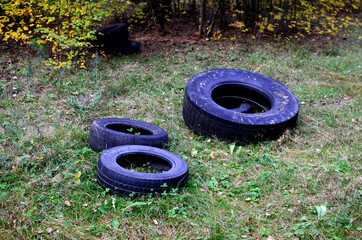 Old rubber tires from a car are thrown into the forest. People pollute the environment harming nature. Ecology conservation concept