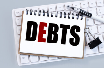 DEBTS. text on white paper on white keyboard