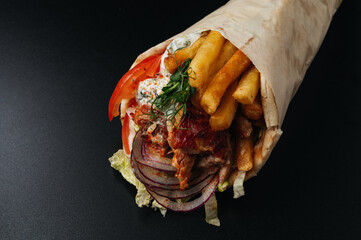 Greek gyros wrapped in pita breads on black background. Gyro pita, shawarma, take away, street food