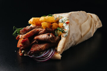 Greek gyros wrapped in pita breads on black background. Gyro pita, shawarma, take away, street food