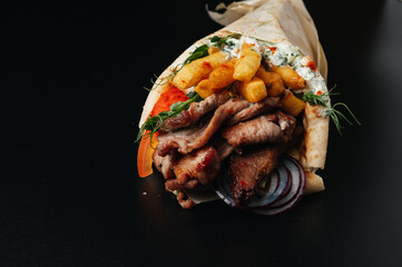 Greek gyros wrapped in pita breads on black background. Gyro pita, shawarma, take away, street food
