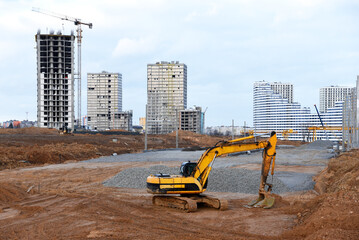 Excavator on earthworks at construction site. Backhoe on road construction. Tower cranes in action...