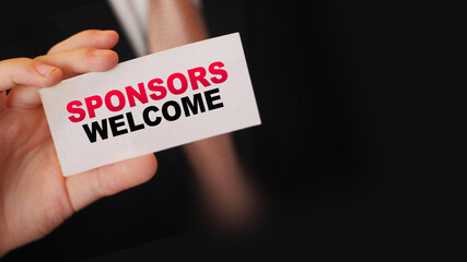 Businessman shows a card with text Sponsors Welcome. Fundrising business concept
