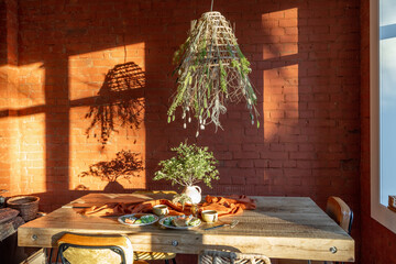 Dining place with a wooden table and straw lampshade in the living room in natural timeless style...