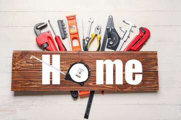 Set of construction tools and wooden board with word HOME on table