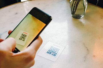 Man scanning the QR code with mobile phone at the restaurant.
