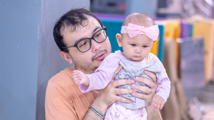 Asian Baby Girl being held by her father who is wearing glasses