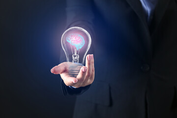 Businesswoman with human brains inside of light bulb on dark background. Concept of business idea