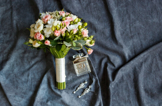 Bridal bouquet of rose flowers, wedding rings and perfume