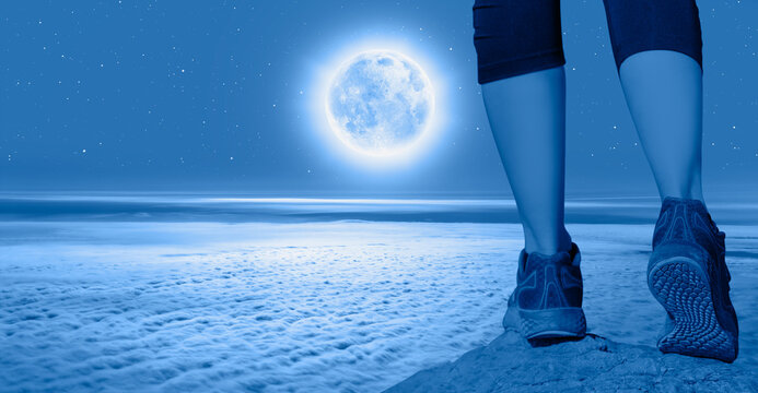Woman walking (hiking) go up  a snowy mountain - Woman walking sport feet on trail healthy lifestyle fitness - Night sky with moon in the clouds "Elements of this imaga NASA"