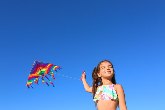 Cute Little Girl Flying Rainbow Kite On Sea Beach